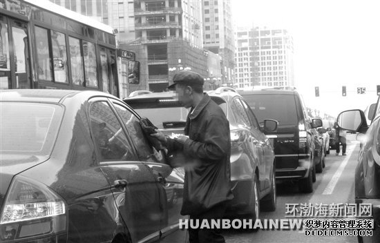 在建設(shè)路新華道路口“擦車(chē)”的行乞者。田菲菲攝